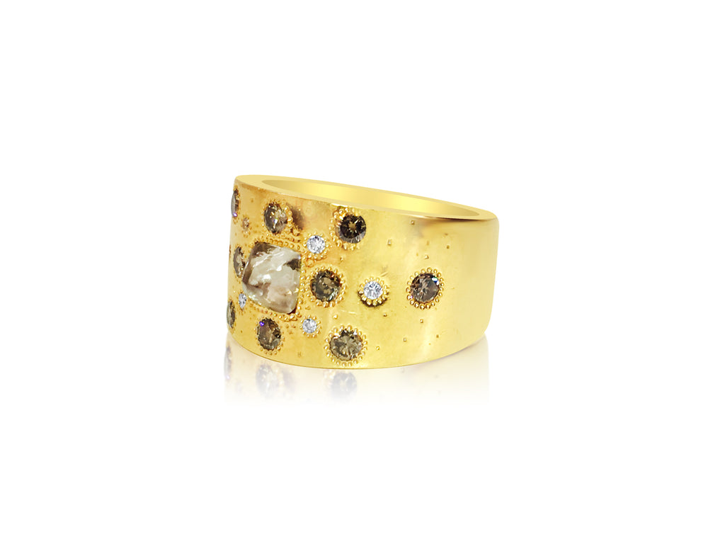 18K yellow gold ring with rough diamond, designed by De Beers, featuring a textured band and natural gemstone setting.
